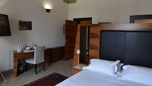 A hotel room with a bed, a desk, a chair, a lamp, and a rug.