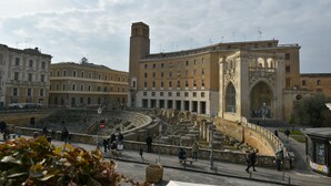 A historic amphitheater with stone steps and a central stage, surrounded by classical architecture.