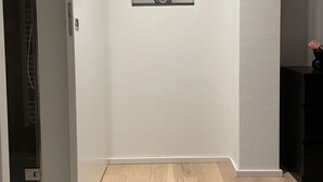 Una habitación con suelo de madera, un ventanal pequeño con una estatua y una puerta.