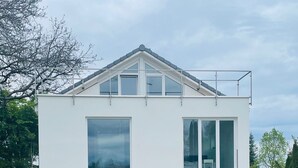 Una casa moderna de dos pisos, con amplios ventanales y un balcón.
