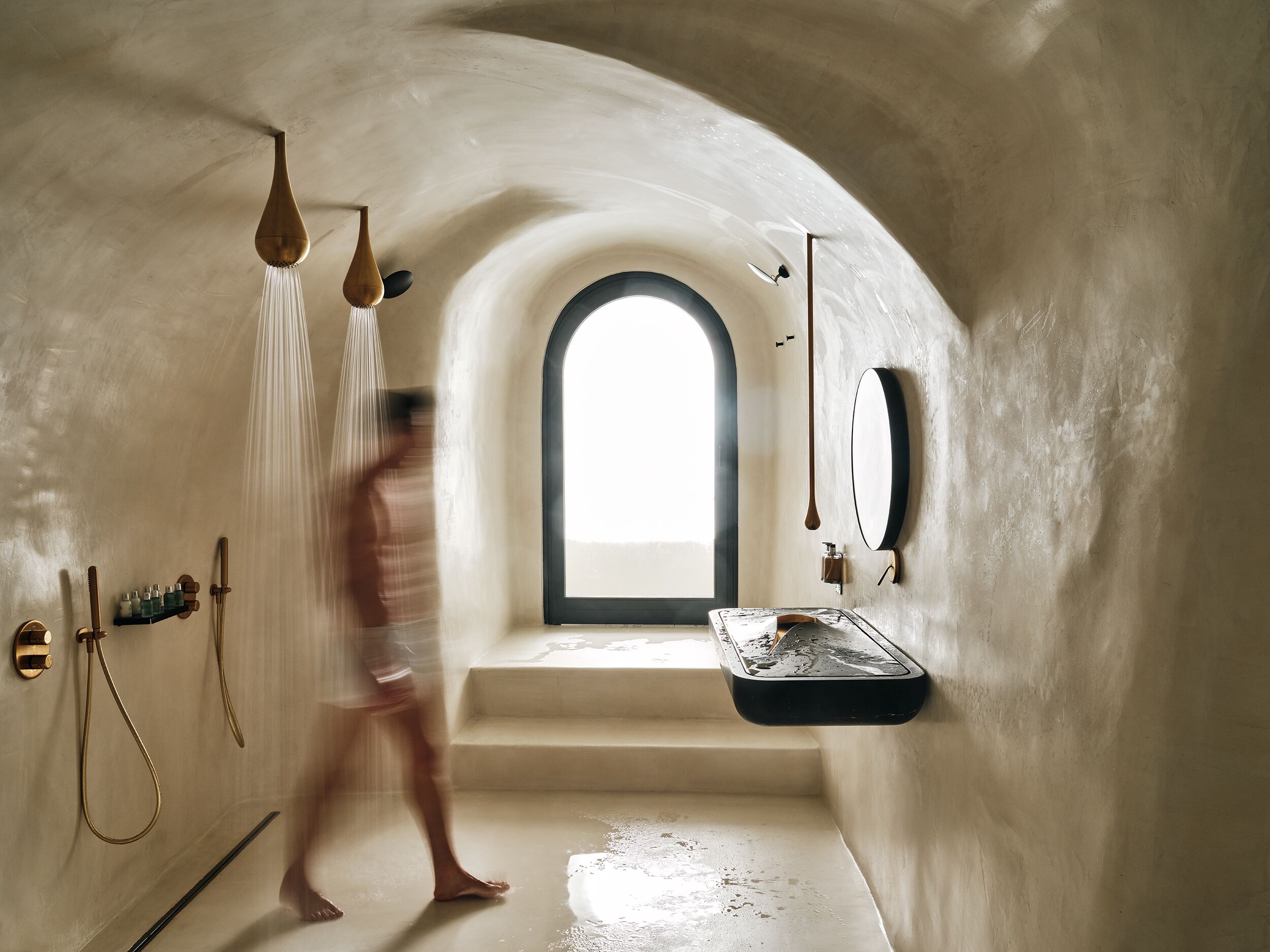 A modern bathroom with a large arched window, a freestanding bathtub, and a minimalist design.