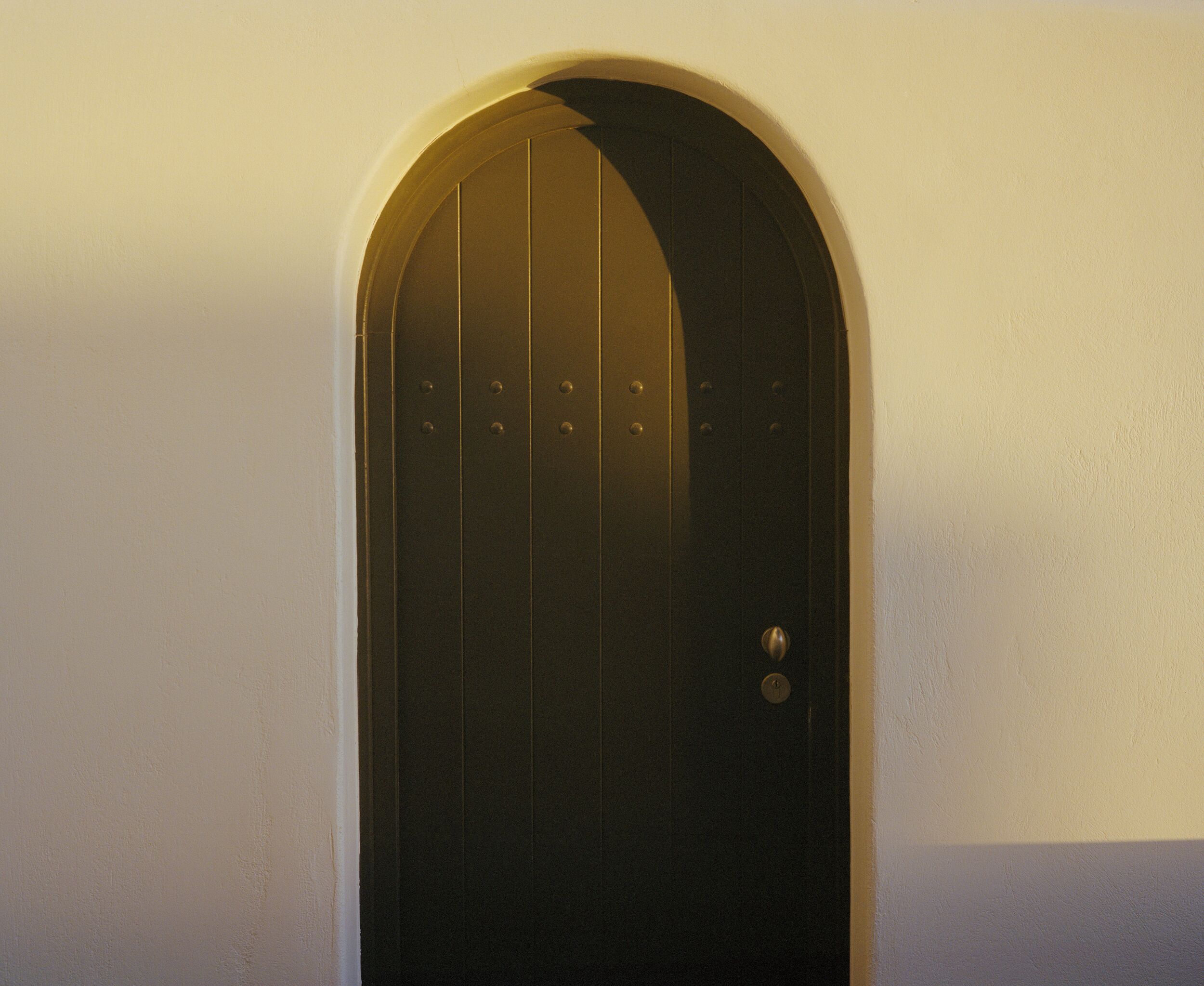 A black door with a round arch and a round handle.