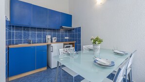 A modern kitchen with blue cabinets and a glass dining table set for two.