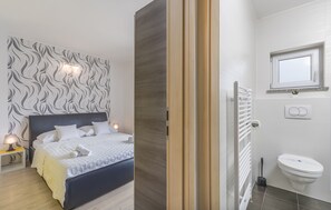 A bedroom with a bed, bedside table, and a wall with a wavy pattern. - Villa Maja 4 Beachfront Apartment (Funtana)