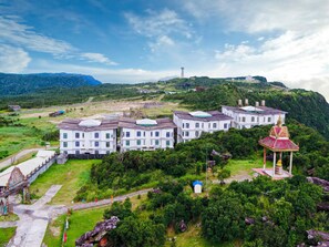 A large, multi-story building with a traditional architectural style, surrounded by lush greenery and hills. - Bokor Inn by Sokha Group (Kampot)