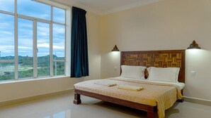 A bedroom with a large window, a bed with a wooden headboard, and two wall-mounted lamps. - Bokor Inn by Sokha Group (Kampot)