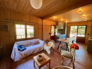 A cozy cabin interior with a bed, a dining table, and a kitchen area.