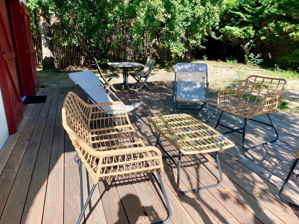Terraza exterior con mobiliario de mimbre, incluyendo dos sillas y una mesa.