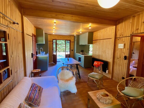 A cozy cabin interior with a wooden interior, a dining area, a kitchen, and a large window.