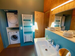 Ein Badezimmer mit Waschmaschine, Trockner, Handtuchhalter, Waschbecken und Spiegel.