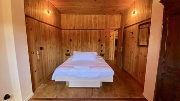 Une pièce aux murs lambrissés, avec un lit, une petite table et un miroir.