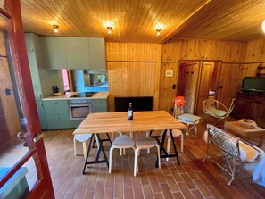 A wooden interior with a dining table, chairs, a kitchen area, and a fireplace. - Idyllic house a few steps from the bay A0388 (Lège-Cap-Ferret)