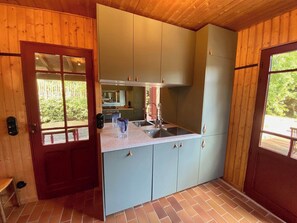 A compact kitchen with a built-in sink, cabinets, and a window overlooking greenery.