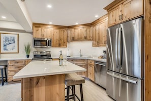 Una cocina moderna con armarios de madera, electrodomésticos de acero inoxidable y una isla central.