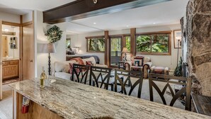 Un salón espacioso con una pared de acento de piedra, una mesa de comedor con sillas y una zona de estar acogedora con un sofá y sillones.