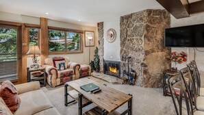 Una sala de estar acogedora con chimenea de piedra, ventanas amplias y asientos cómodos.