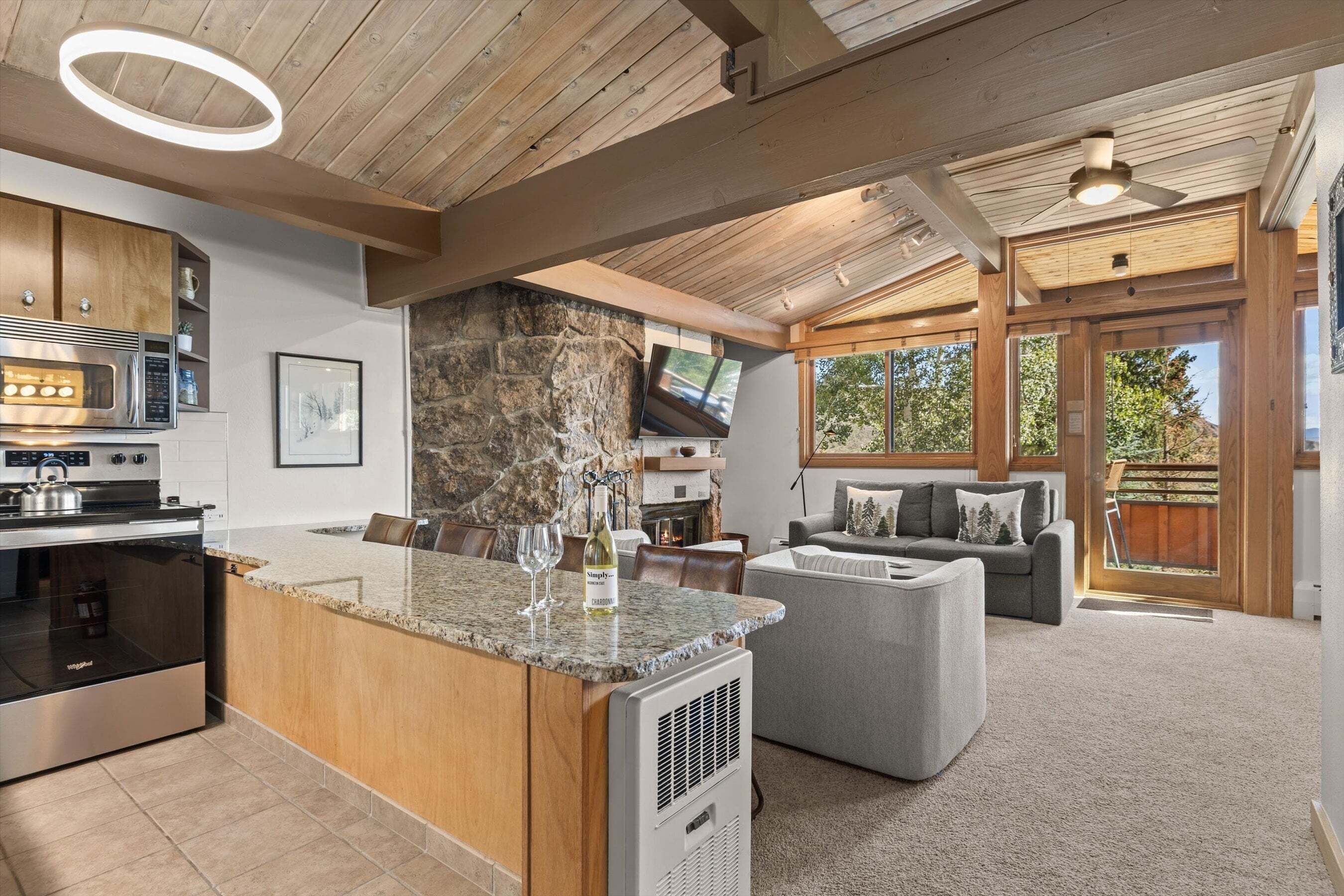 A modern kitchen with granite countertops, a built-in oven, and a stone accent wall.