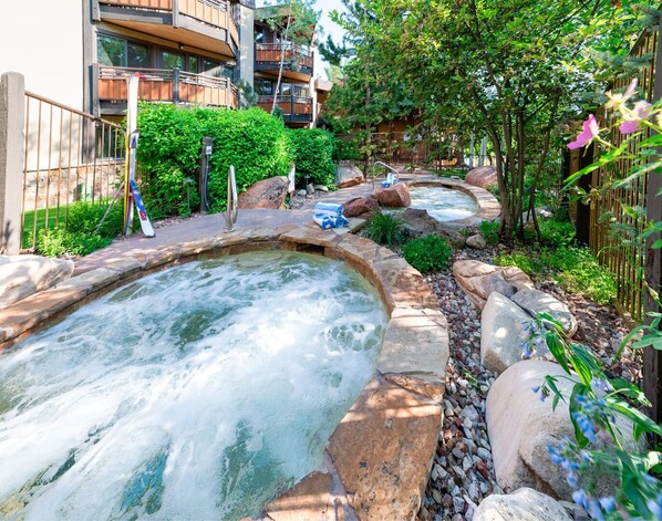 Zona de spa con jacuzzis rodeados de rocas y plantas.