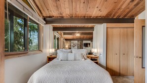 Ein Schlafzimmer mit einem großen Bett, Holzboden, Steinwand und einem Fernseher an der Wand.