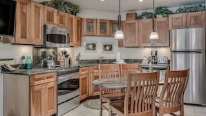 Una cocina moderna con armarios de madera, electrodomésticos de acero inoxidable y una isla central con sillas.