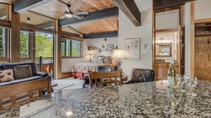 Un vaste espace de vie doté d’un grand plafond en bois, d’une table à manger en granit, d’un canapé et d’un lit avec une tête de lit en bois.