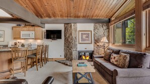 Un salon chaleureux avec une cheminée, un plafond en bois et un mur en pierre.