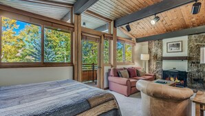 A cozy room with a large bed, a pink sofa, and a stone fireplace.