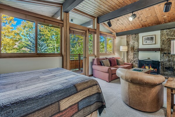 A cozy room with a large bed, a pink sofa, and a stone fireplace.