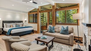 Ein modernes Schlafzimmer mit einem großen Bett, einer Couch und einem Couchtisch. Holzdeckenbalken und große Fenster sind vorhanden.