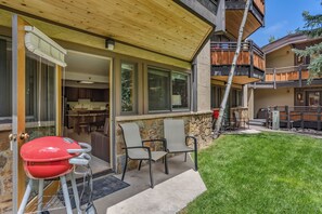 A covered patio with outdoor seating, a barbecue grill, and a stone wall. - 🏔️Ski-In, Ski-Out~Hot Tub~Studio Standard 302🏔️ (Snowmass Village)
