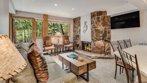 Una sala de estar moderna con chimenea de piedra, asientos cómodos y un televisor grande montado en la pared.