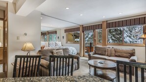 Una sala de estar moderna con una cama grande, un sofá, una mesa de centro y un comedor con una mesa de granito.
