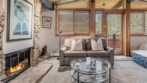 Ein gemütliches Wohnzimmer mit Kamin aus Stein, einer Couch und einem Glastisch.