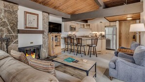 Una sala de estar acogedora con chimenea, pared de piedra y techo de madera.
