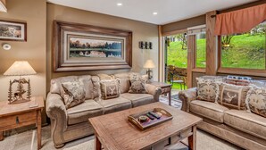 A living room with two sofas, a coffee table, and a framed landscape painting.