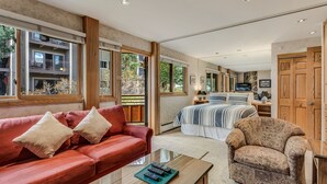 A spacious living area with a red sofa, a patterned armchair, and a glass coffee table. - 🏔️Slopeside~Hot Tub~Studio Deluxe 407🏔️ (Snowmass Village)