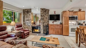 A modern living room with a fireplace, leather sofa, and a dining area with wooden furniture. - 🏔️Slopeside~Hot Tub~Studio Deluxe 408🏔️ (Snowmass Village)