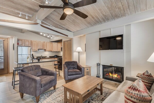 Una sala de estar moderna con chimenea, televisor y ventilador de techo.