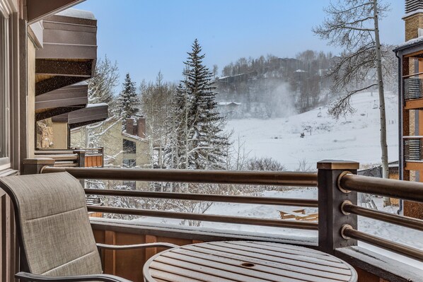 Ein Balkon mit Blick auf eine verschneite Landschaft, darunter ein Sessellift und Bäume.