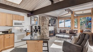 A modern kitchen with a microwave, stove, and wooden cabinets. There is a stone accent wall, a fireplace, and a seating area with a sofa and a recliner. - 🏔️Slopeside~Hot Tub~Top Floor~Studio Deluxe 414🏔️ (Snowmass Village)