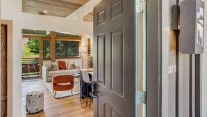 A modern living room with a sofa, chairs, and a dining area. A large door with a number plate is visible. - 🏔️New Remodel~Slopeside~Hot Tub~Top Floor~Studio Premier 415🏔️ (Snowmass Village)