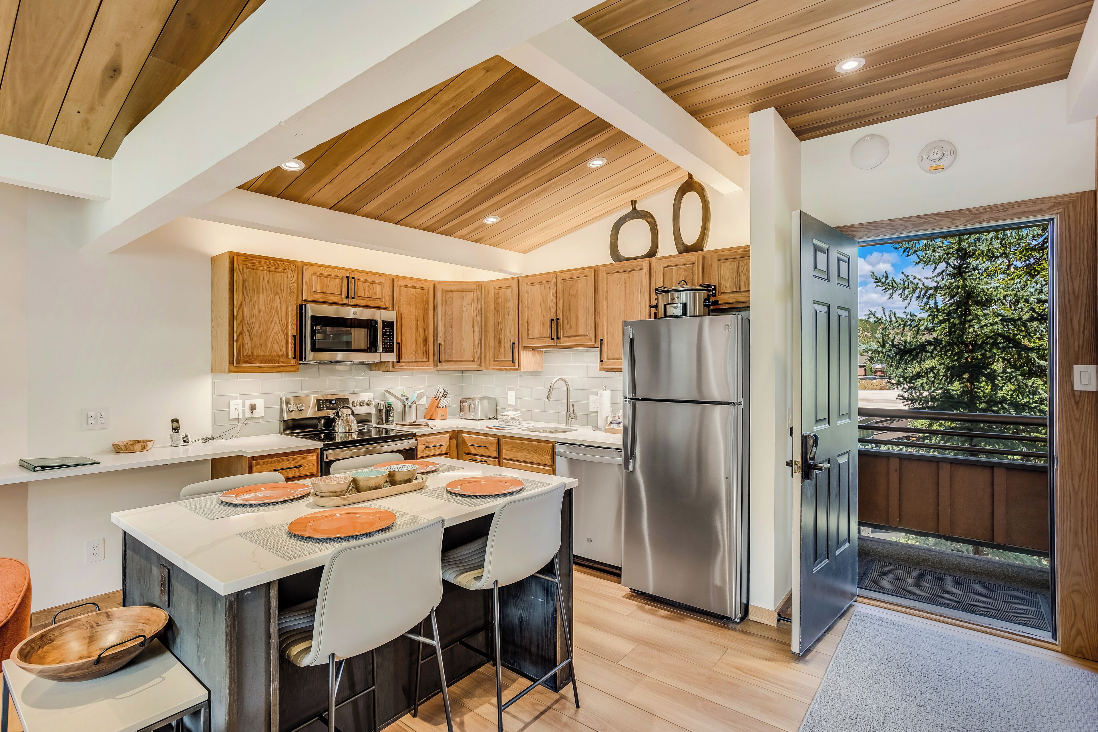 A modern kitchen with wooden cabinets, stainless steel appliances, and a central island with seating.