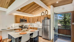 A modern kitchen with wooden cabinets, stainless steel appliances, and a central island with seating. - 🏔️New Remodel~Slopeside~Hot Tub~Top Floor~Studio Premier 415🏔️ (Snowmass Village)
