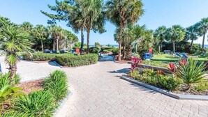 A paved pathway leading to a pool area surrounded by palm trees and greenery. - Contemporary 3BR Beach Colony Resort -  Oceanfront (Myrtle Beach)