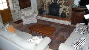 Una sala de estar acogedora con chimenea de piedra, un sofá, una mesa de centro y una estantería.