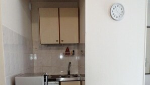 A compact kitchen with a microwave, refrigerator, and sink. There is a dining table with a checkered tablecloth. - Les Minimes LA Rochelle Charente Maritime (La Rochelle)