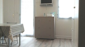 A room with a dining table, a television mounted on the wall, and a cabinet. - Les Minimes LA Rochelle Charente Maritime (La Rochelle)