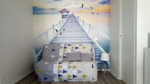 A bedroom with a bed at the end of a painted pier leading to a sunset scene. - Les Minimes LA Rochelle Charente Maritime (La Rochelle)