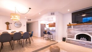 A modern kitchen with wooden cabinets, a built-in stove, and a large flat-screen TV above the counter. - 🌵 Cozy Cactus Home near Old Town & ASU 🌵 Pool ⭐ Game Room ⭐ BBQ ⭐ Fire Pit ⭐ (Tempe)