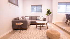 A modern living room with a sectional sofa, a round coffee table, and a small side table. - 🌵 Cozy Cactus Home near Old Town & ASU 🌵 Pool ⭐ Game Room ⭐ BBQ ⭐ Fire Pit ⭐ (Tempe)